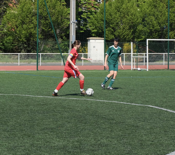 Photo montrant un match de football féminin sur un terrain extérieur.
